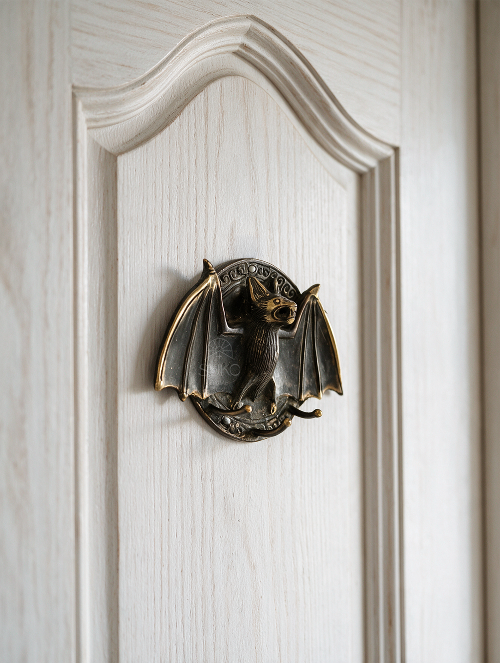 Brass bat door knocker featuring a classic functional ring