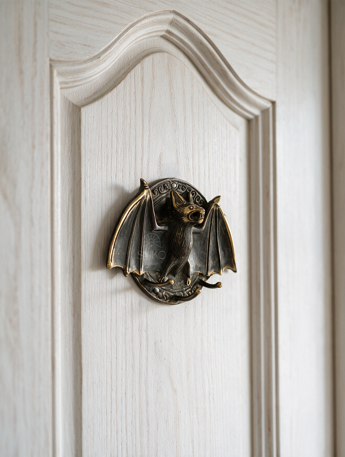 Brass bat door knocker featuring a classic functional ring