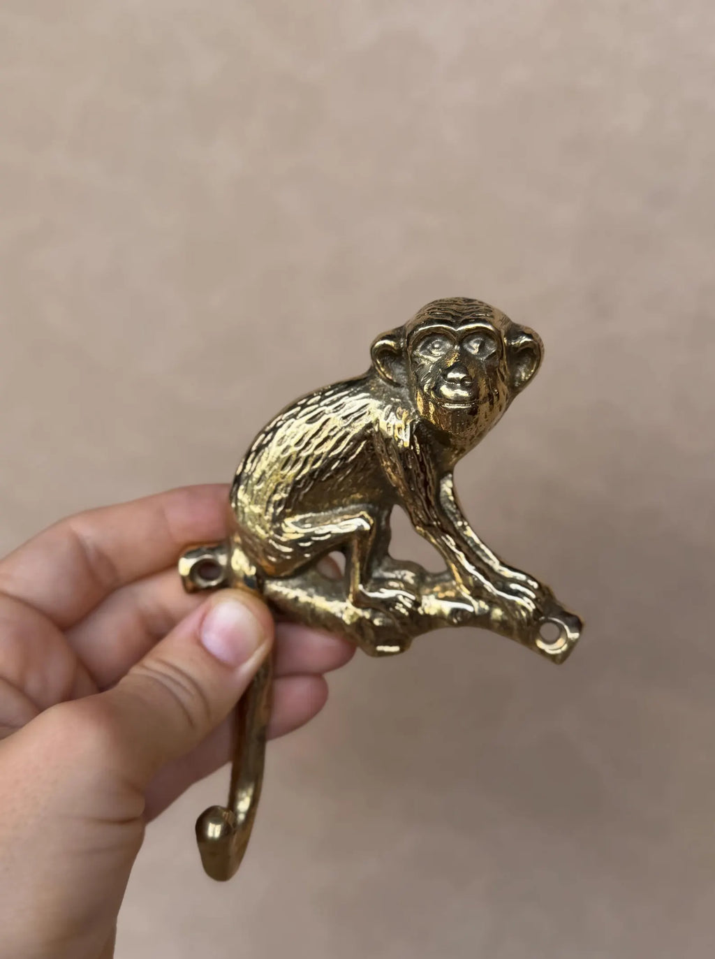 Close-up of the sculpted gold brass monkey sitting on a branch, held in hand