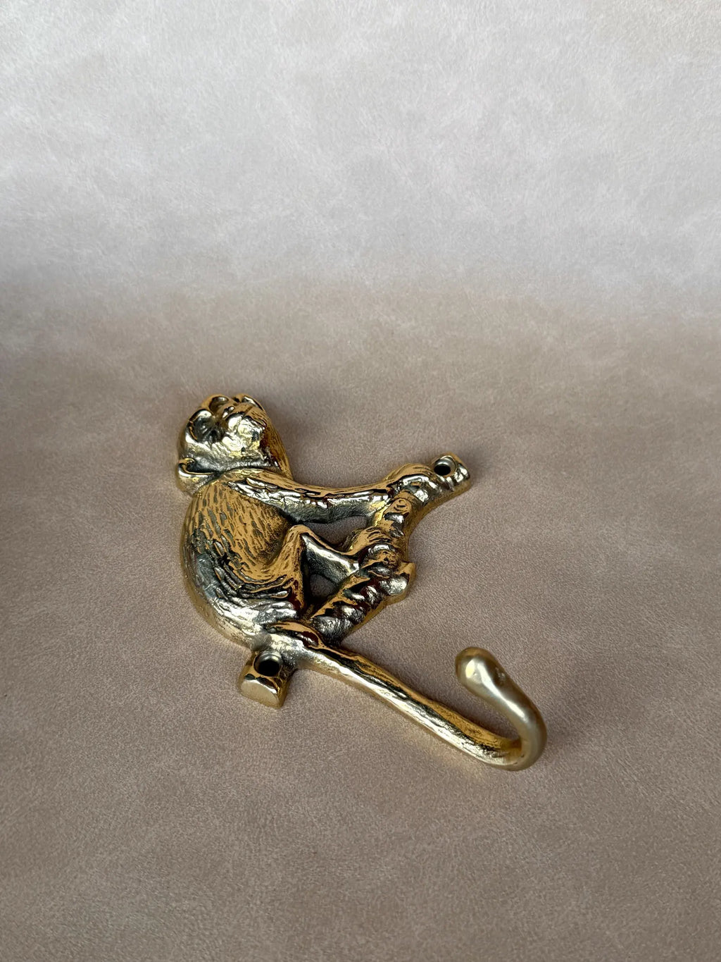 Gold brass monkey hook lying on its side, showing the curve of the hook