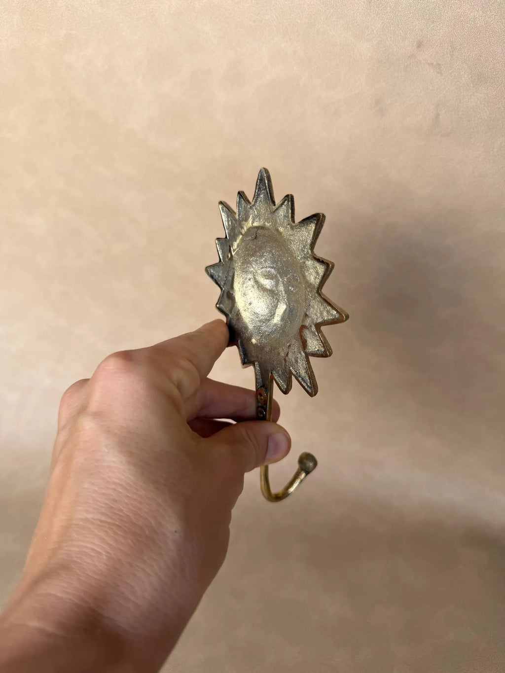 Side view of the brass sun hook held at an angle to show its depth