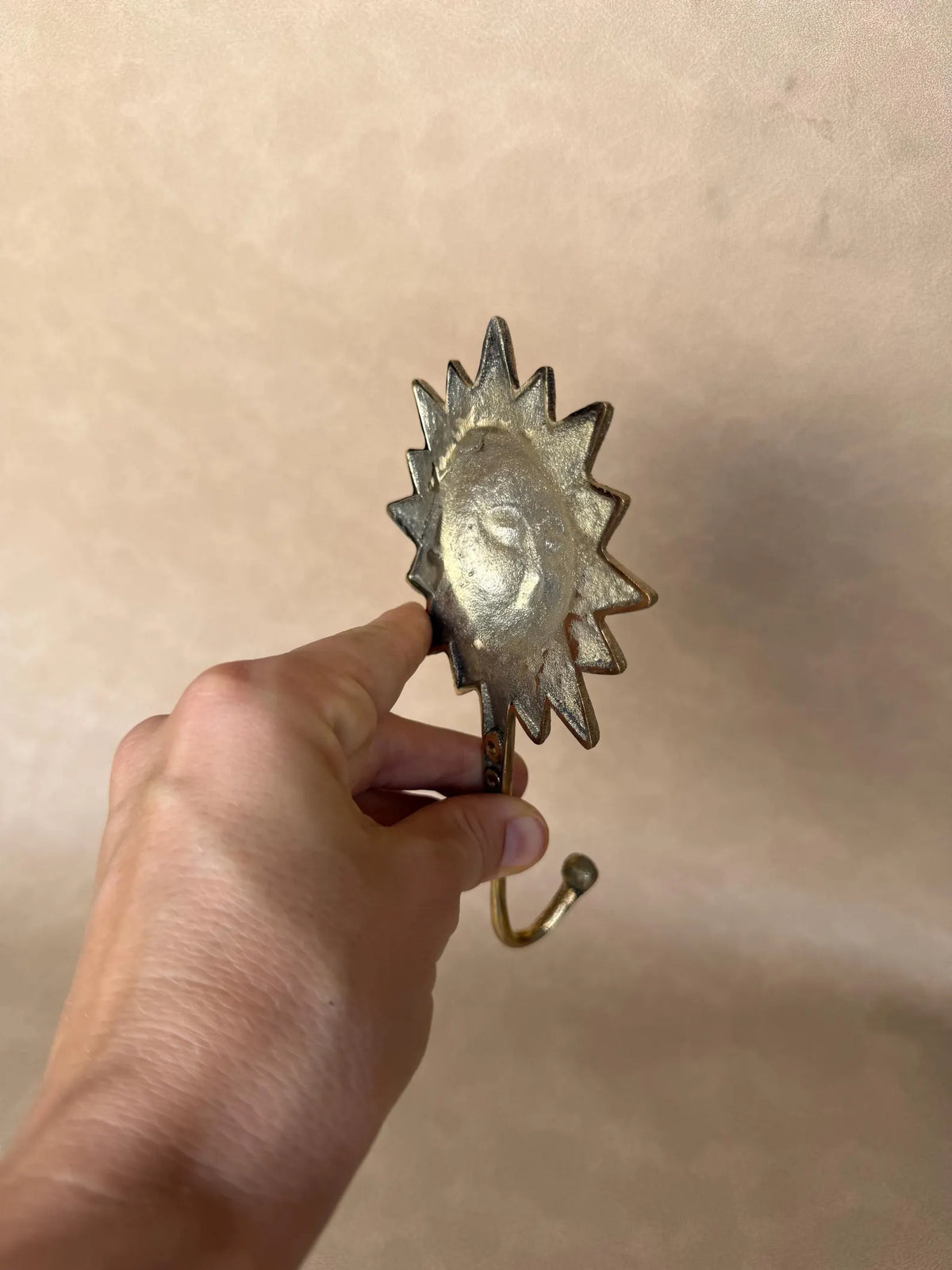 Side view of the brass sun hook held at an angle to show its depth
