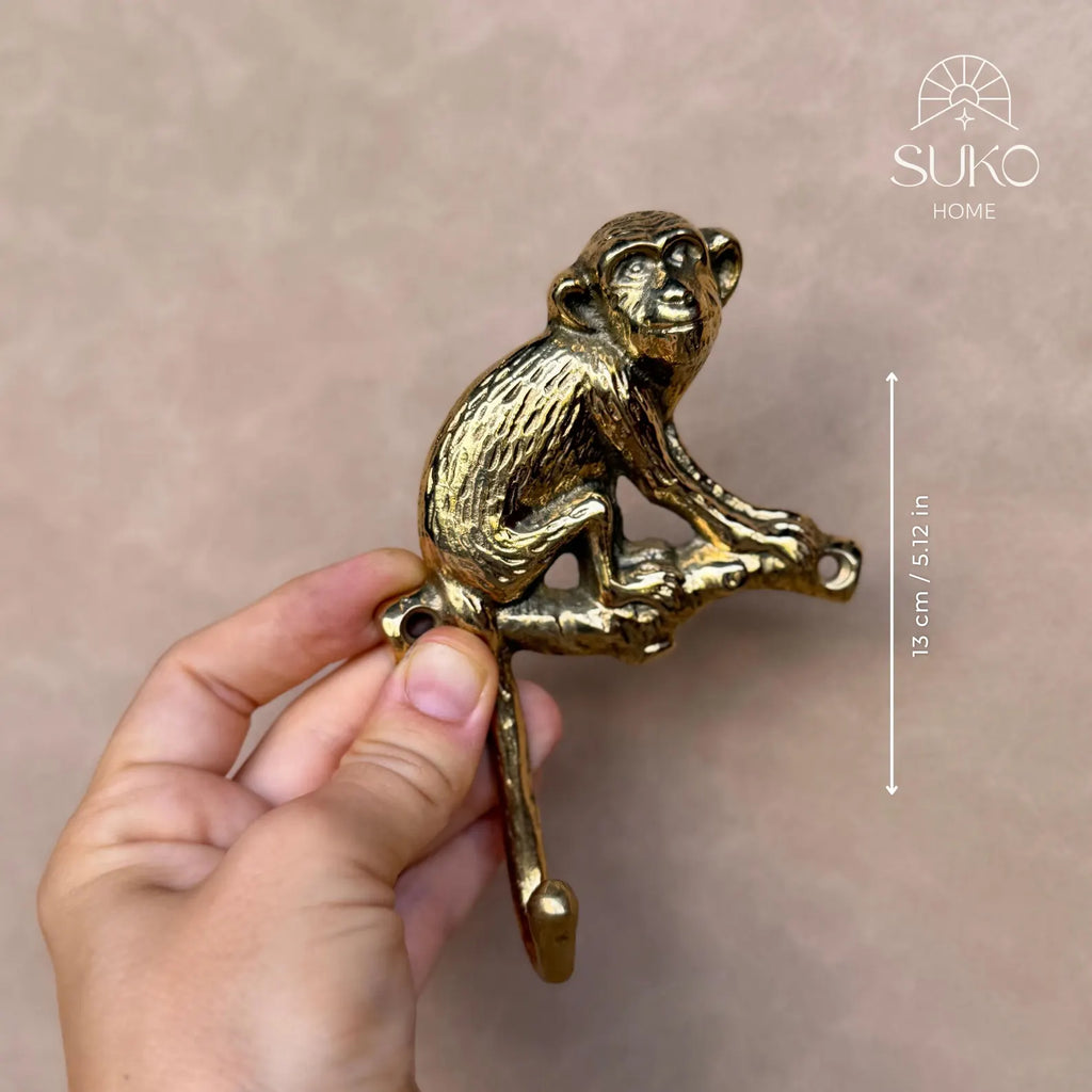 Hand holding the brass monkey hook with a size marker showing its length