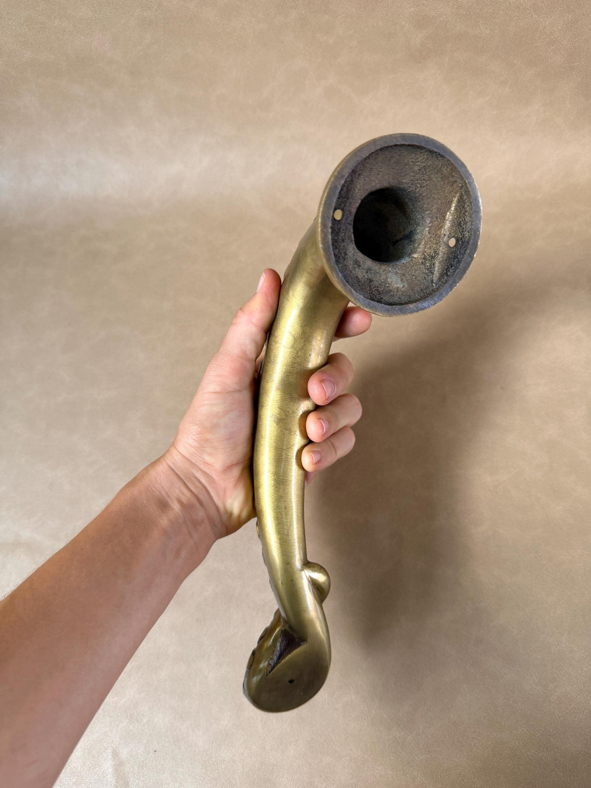 Hollow mounting end of the brass octopus tentacle door handle, held upright in a hand