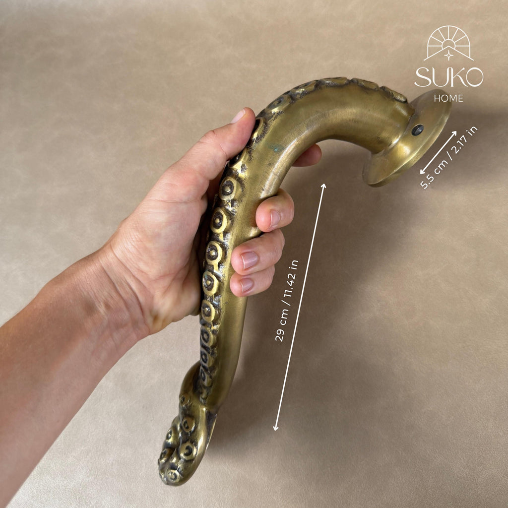 Hand holding the brass octopus tentacle door handle with a size marker showing its length