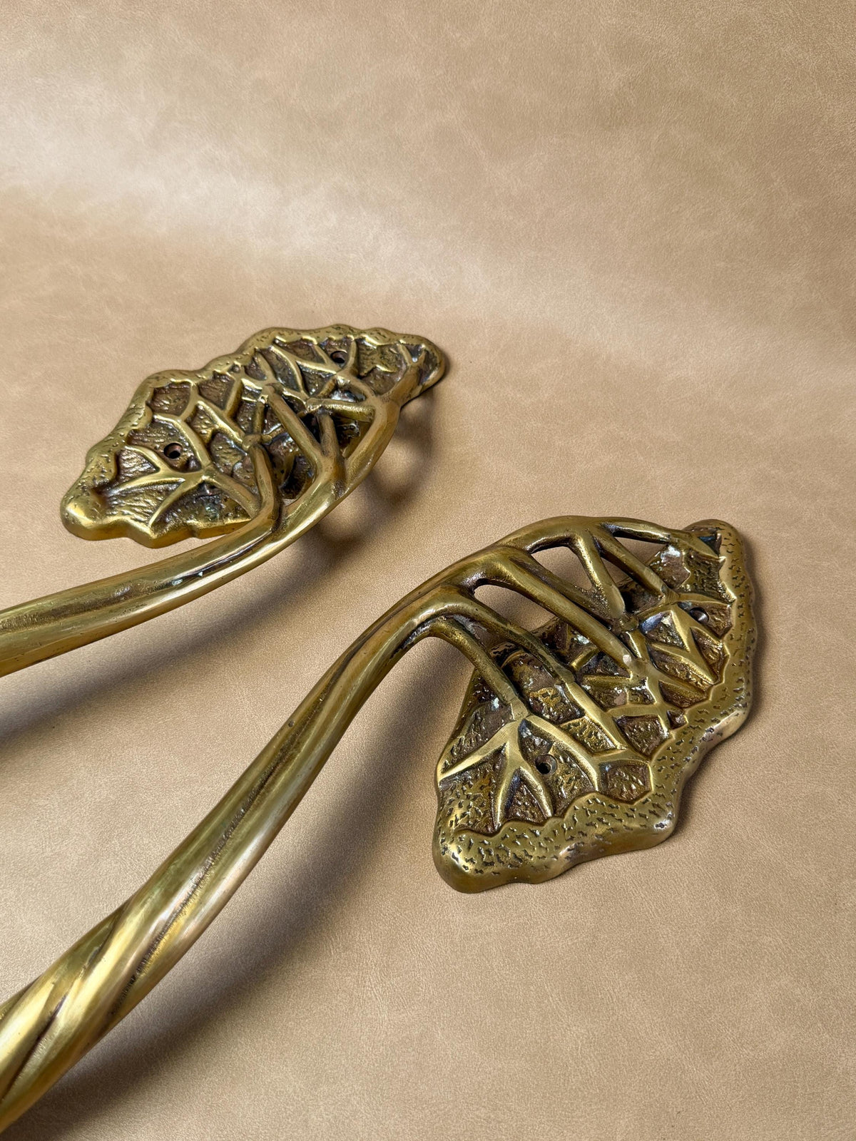 Close-up of the openwork leaf canopies on two brass tree handles