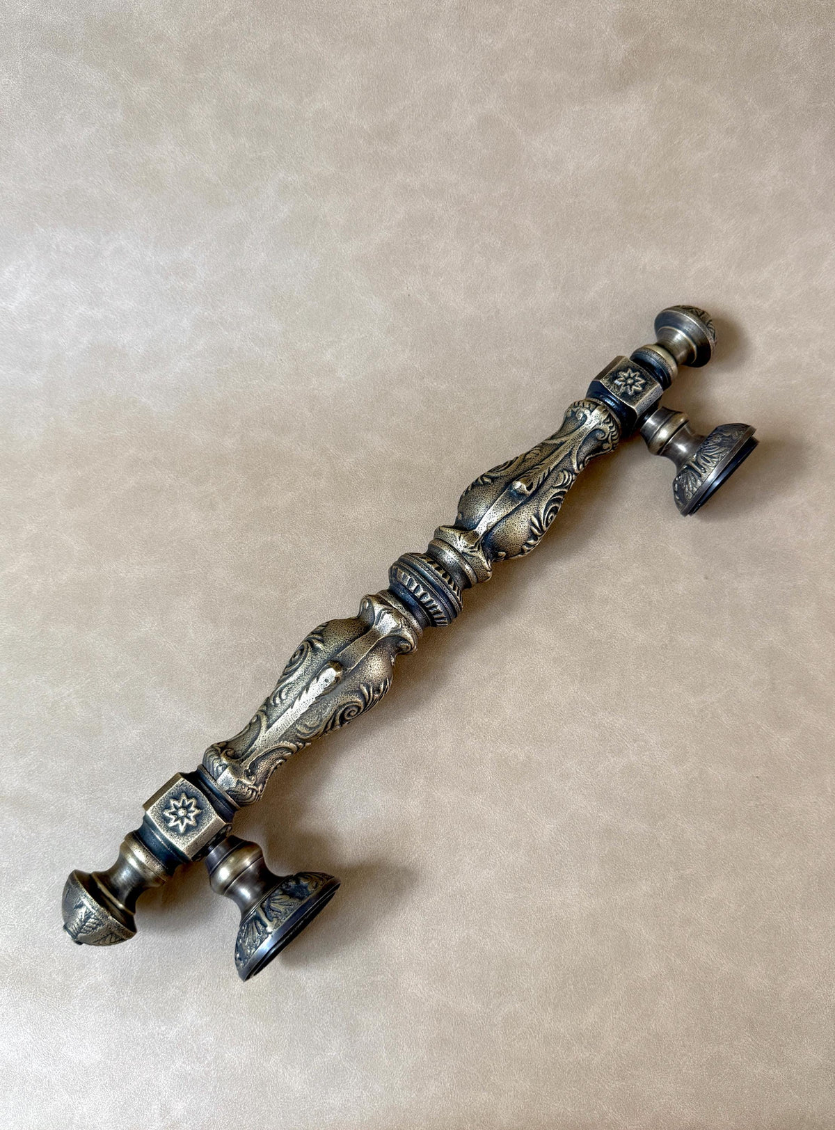 Central grip with decorative ridges and square mounting plates embossed with a star-shaped flower