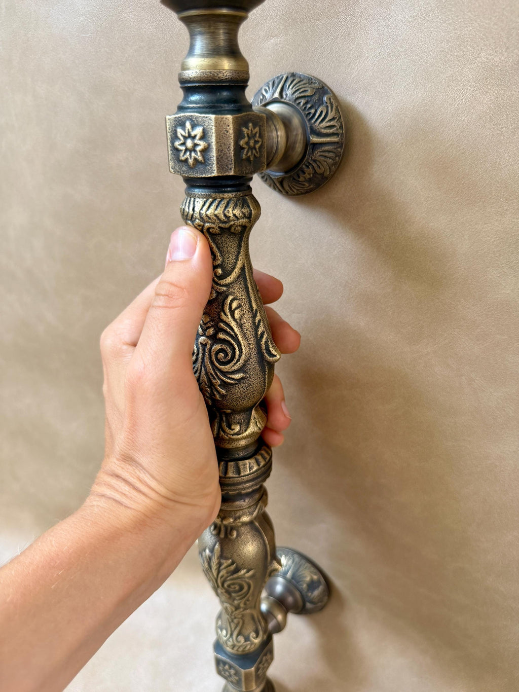 Floral relief and star accents on the square mounting blocks of the antique brass door pull