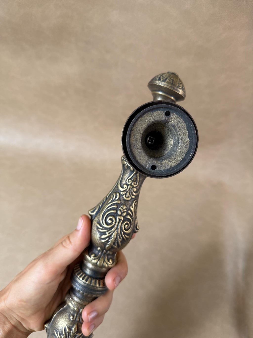 Round mounting base of the brass door pull with two screw holes and a decorative finial