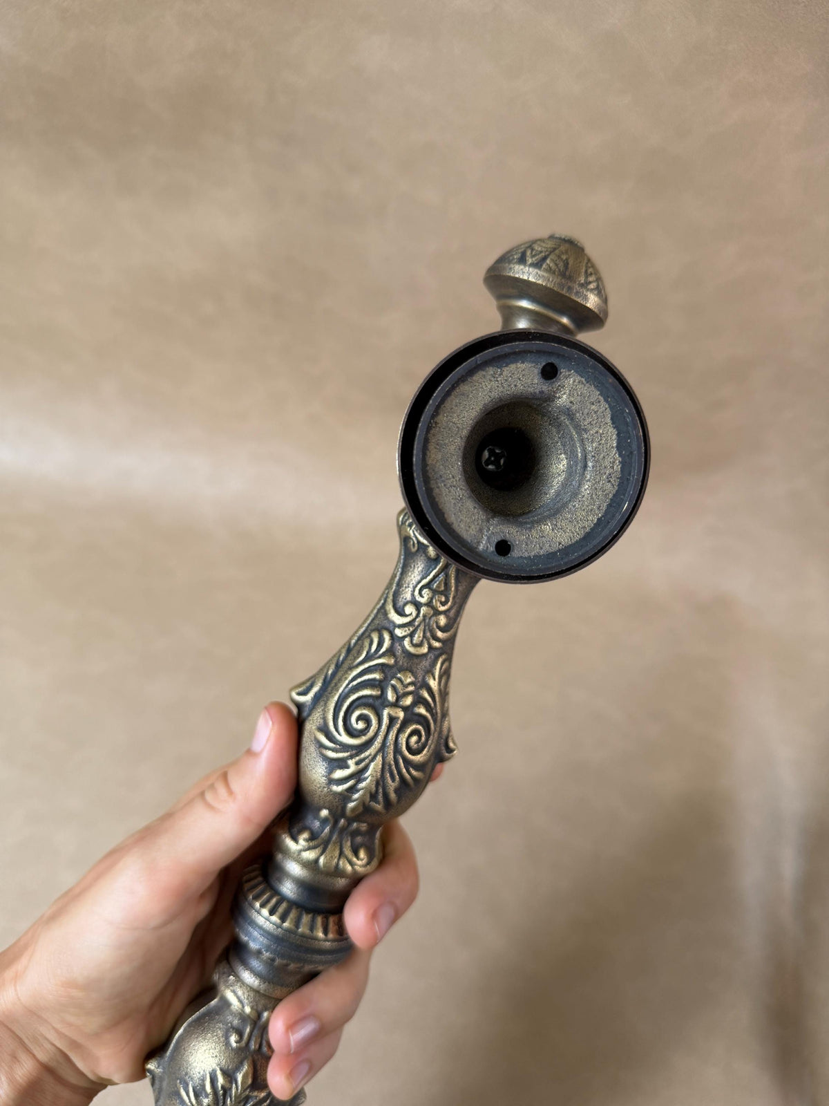 Round mounting base of the brass door pull with two screw holes and a decorative finial