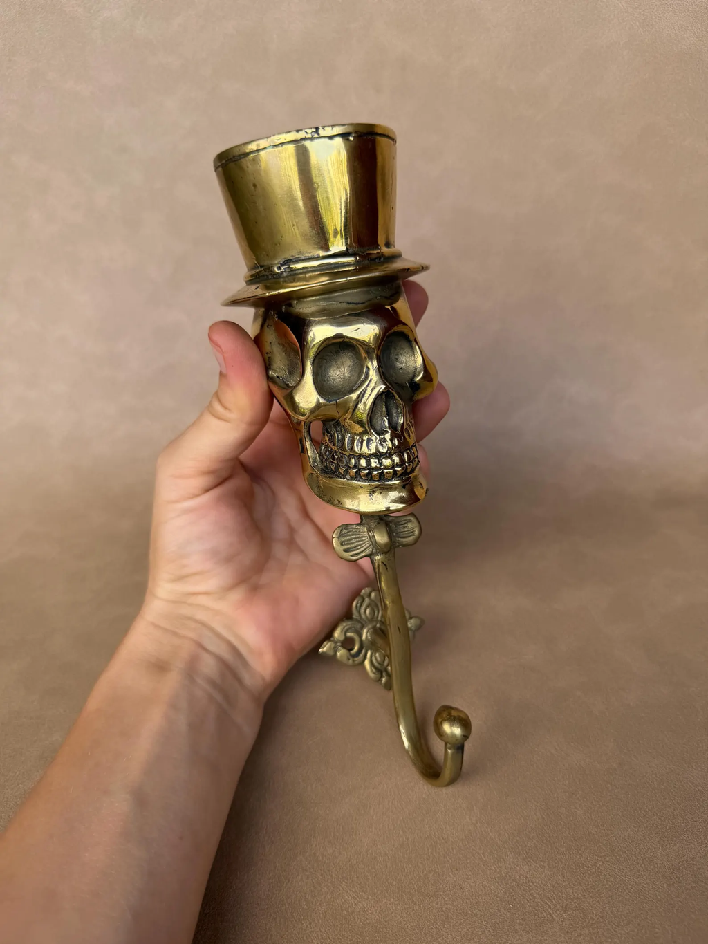 Brass skull top hat hook seen from below, showing the side of the hat and the hook curve