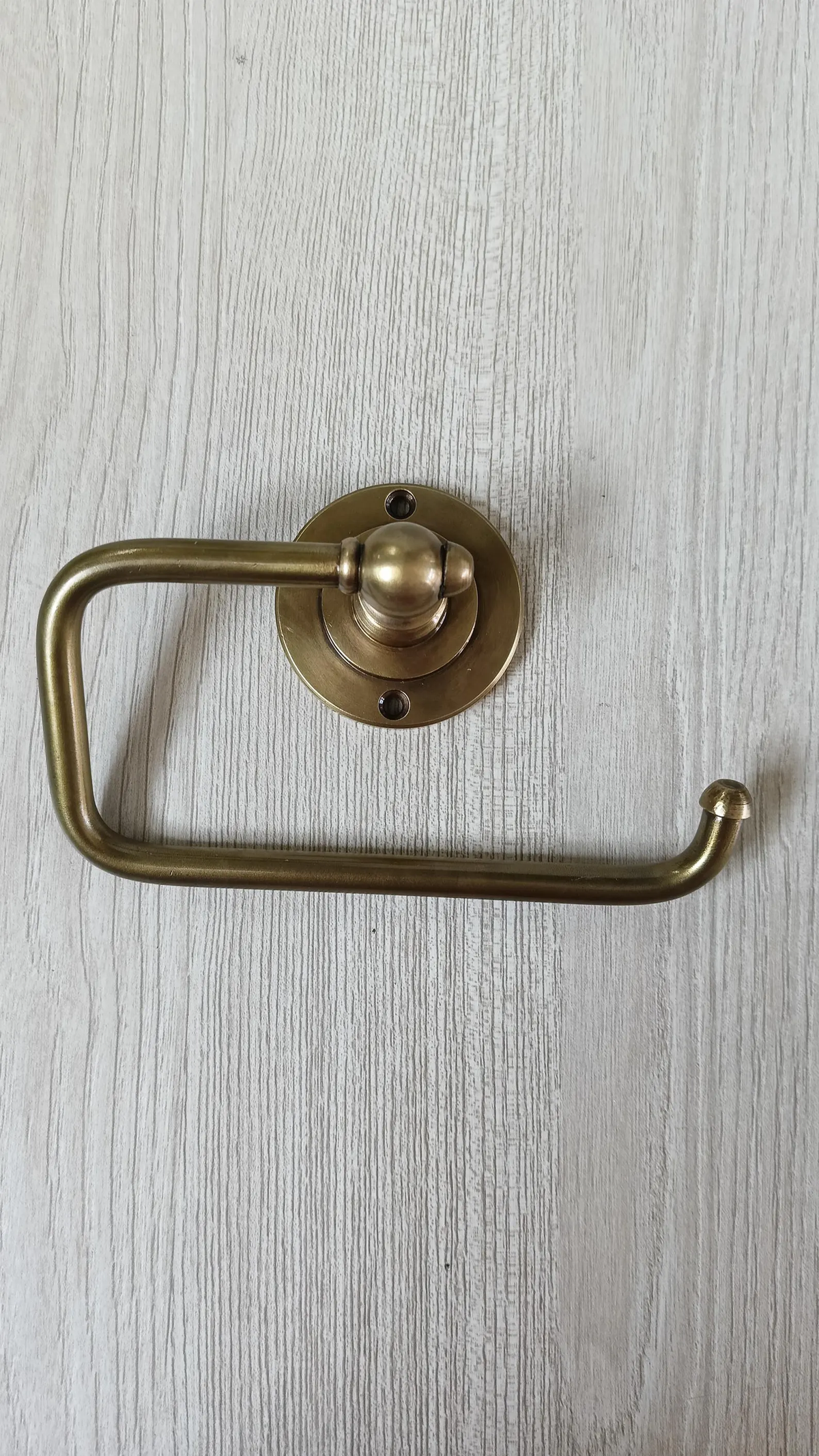 Wall mounted brass toilet roll holder with round backplate and open side arm