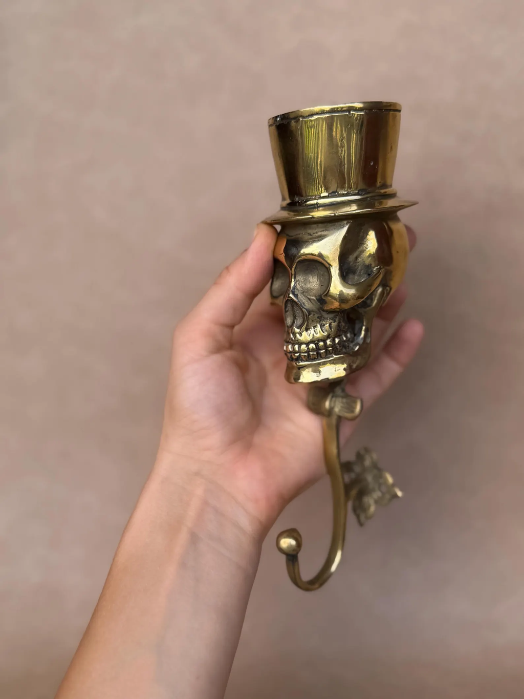 Full length of the 21 cm brass skull coat hook against a beige background