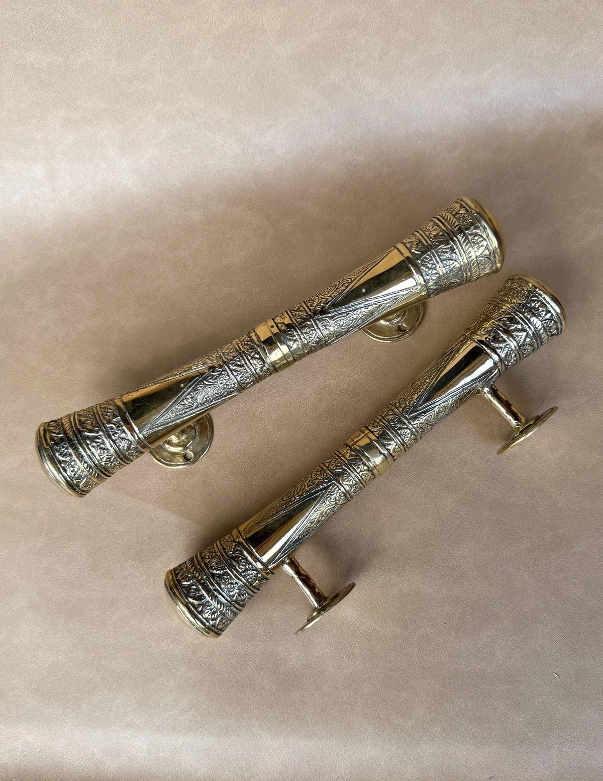 Set of two engraved brass pull handles lying side by side