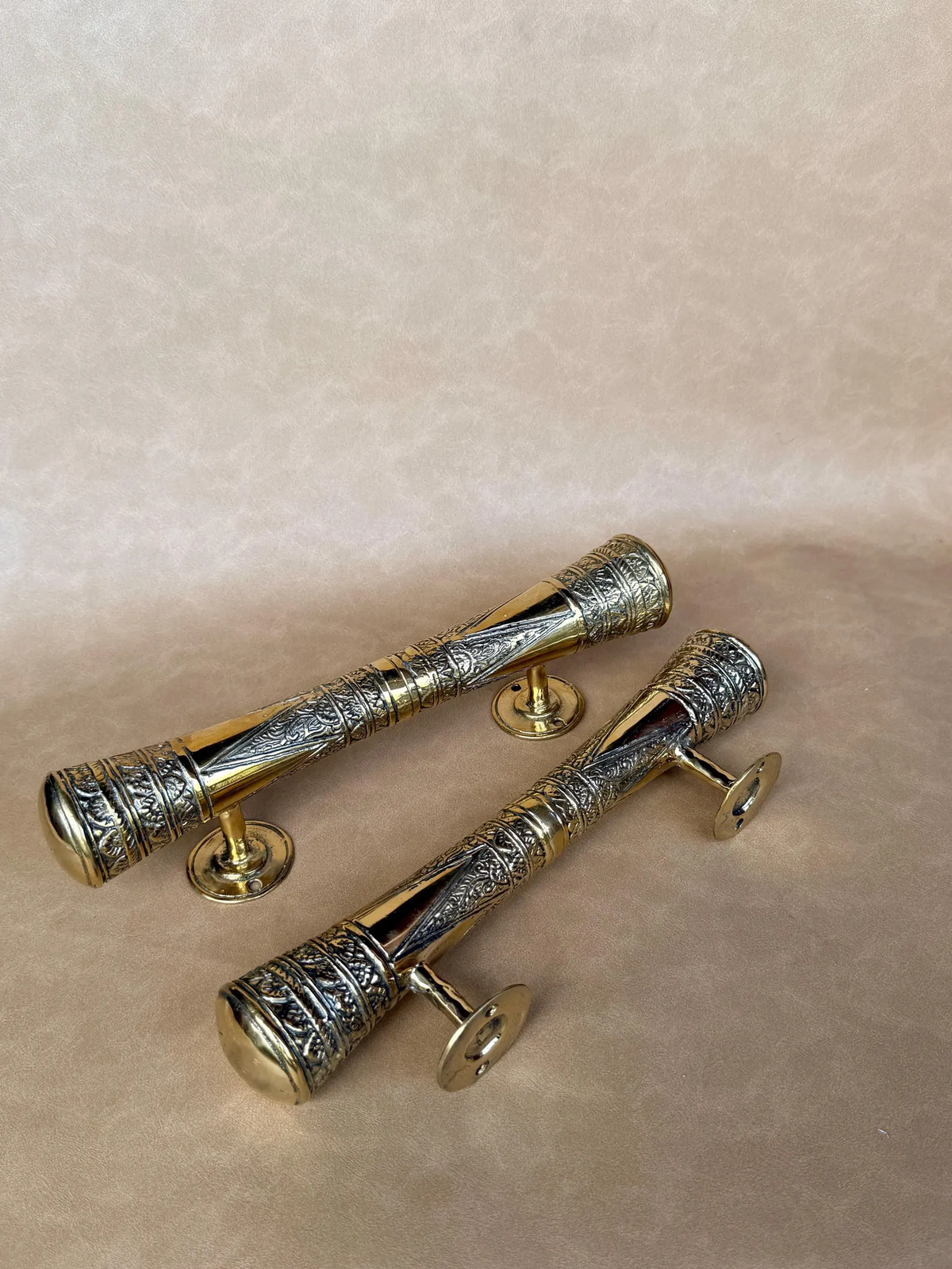 Pair of gold-finish brass oriental pull handles lying on a beige background
