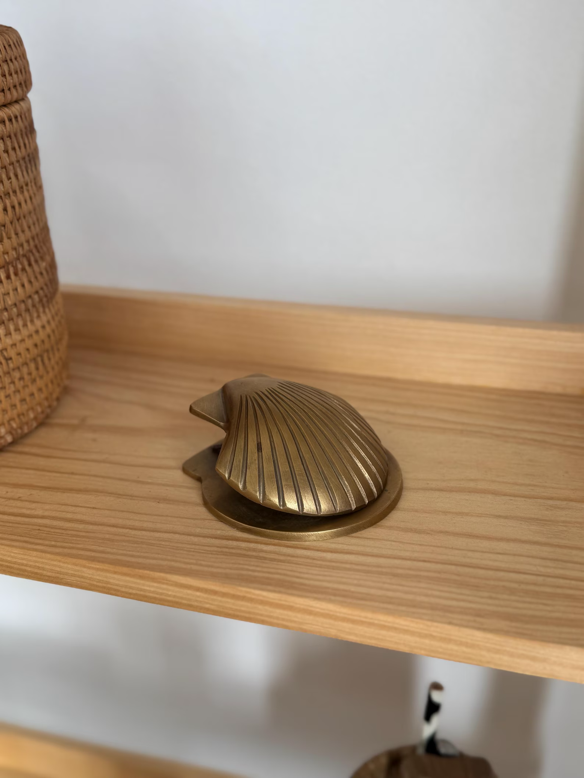 Brass shell clip lying flat on a light wooden shelf