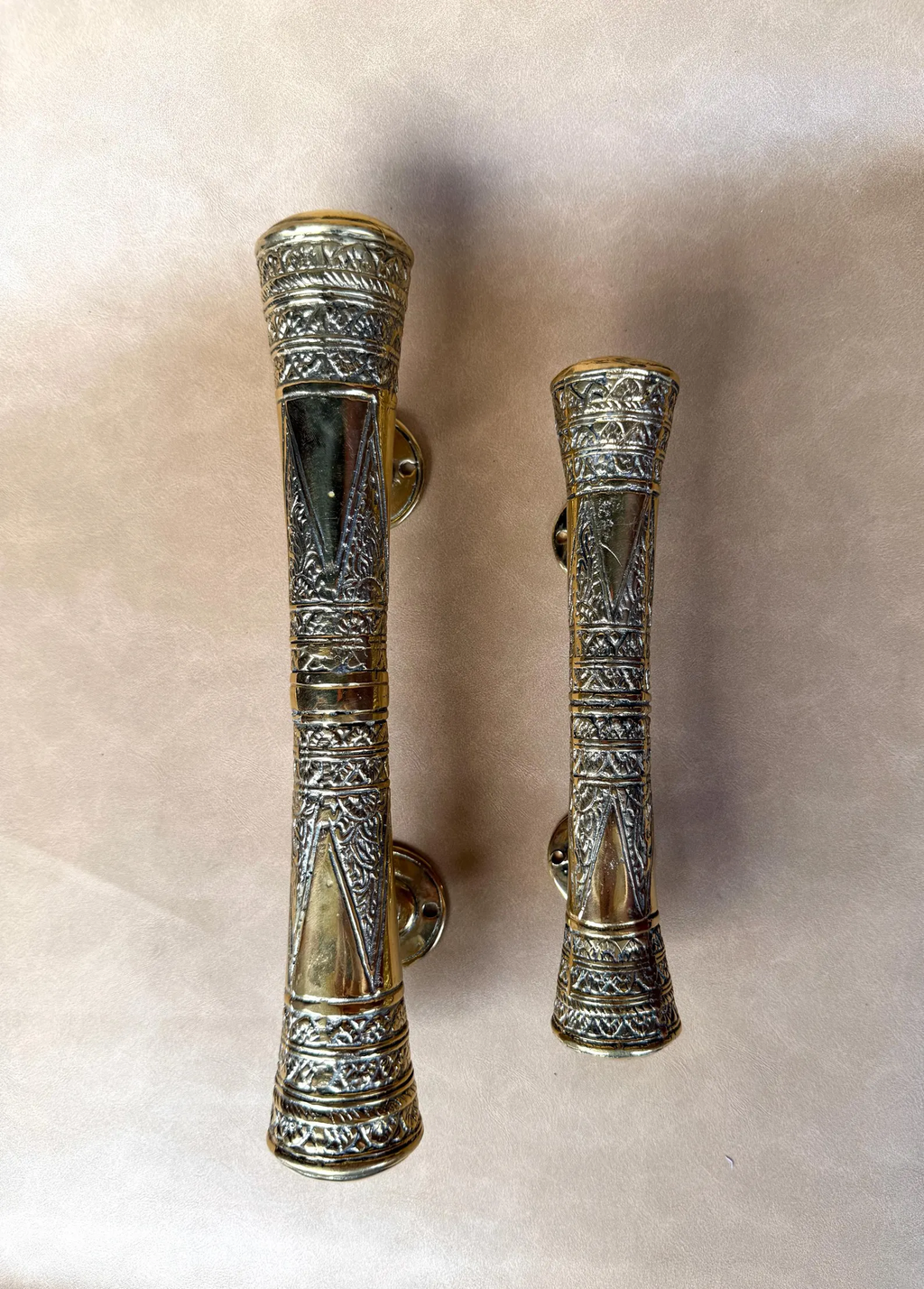 Two brass oriental pull handles in different sizes side by side
