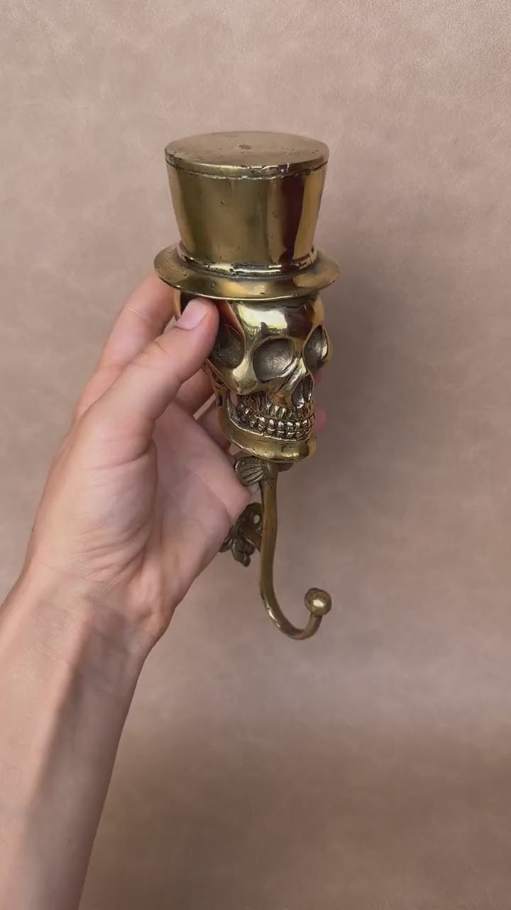 Video of a hand holding the brass skull wall hook with a top hat
